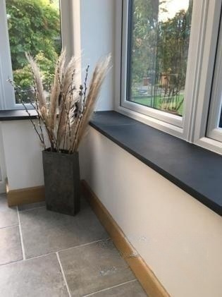Подоконники из тёмно-серого камня вдоль эркерных окон загородного дома